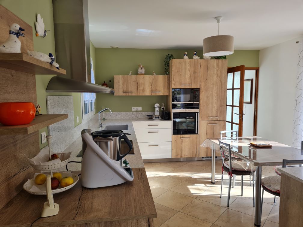 une cuisine à l'allure moderne et naturelle. Les façades en bois et le plan de travail en quartz blanc fusionnent pour créer un équilibre entre modernité et chaleur naturelle. Cette combinaison offre une esthétique contemporaine tout en évoquant la beauté organique du bois. cuisine-chaleureuse-conviviale-bois-quartz