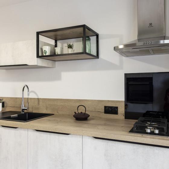 Plan de travail en bois avec évier noir encastré et crédence assortie, installé dans une cuisine design sur-mesure à Châteaubriant