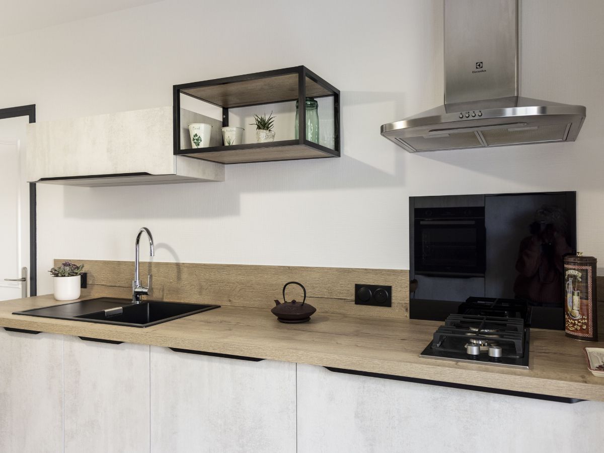 Plan de travail en bois avec évier noir encastré et crédence assortie, installé dans une cuisine design sur-mesure à Châteaubriant