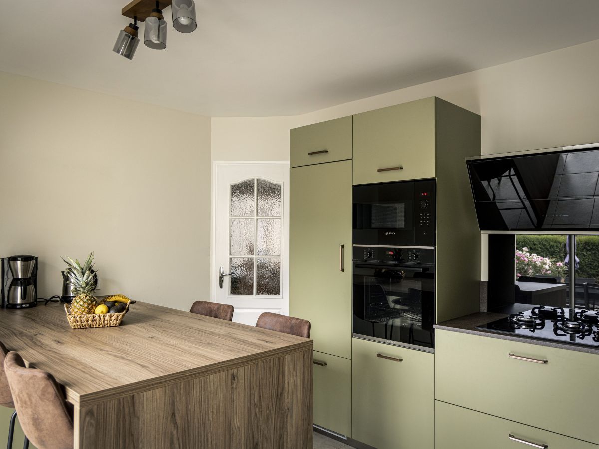 Îlot central en bois avec table intégrée et colonnes d'électroménager encastrées dans une cuisine design à Châteaubriant